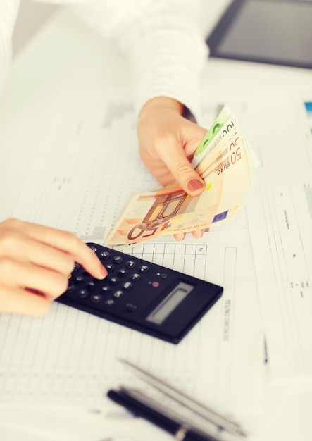 business, office, household, school, tax and education concept - woman hand with calculator and euro money