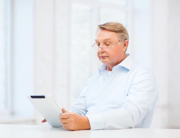 business, office, oldness, school and education concept - old man wearing eyeglasses with tablet computer at home