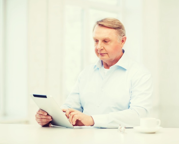 business, office, oldness, school and education concept - old man wearing eyeglasses with tablet pc computer at home