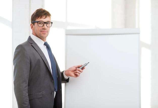 business, office, school and education concept - businessman pointing to flip board in office