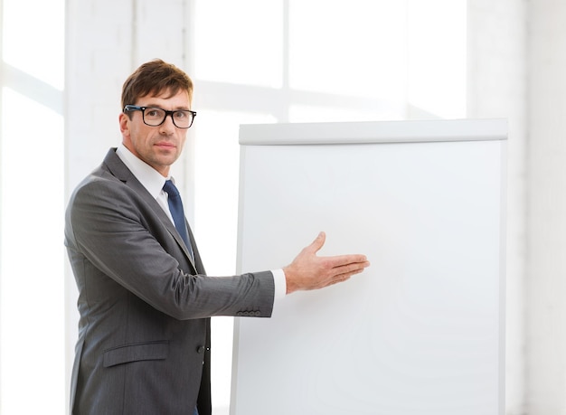 business, office, school and education concept - businessman pointing to flip board in office