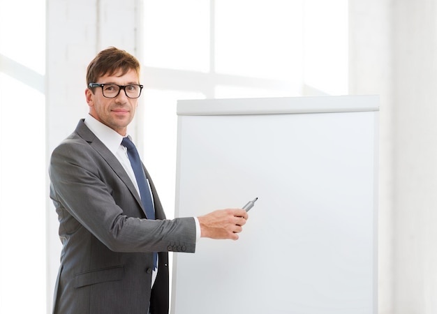 business, office, school and education concept - businessman pointing to flip board in office