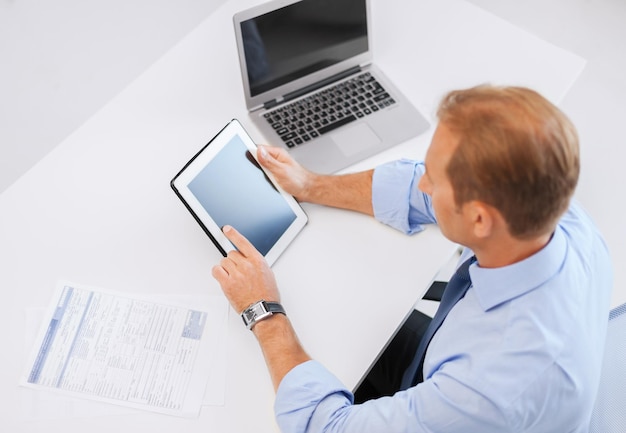 business, office, school and education concept - businessman with tablet pc and papers in office