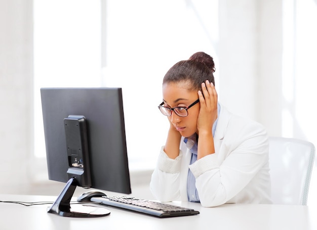 business, office, school and education concept - stressed african businesswoman with computer at work