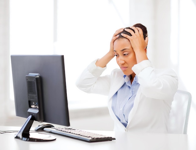 business, office, school and education concept - stressed african businesswoman with computer at work