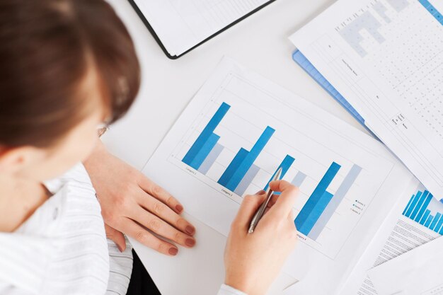 business, office, school and education concept - woman hand with charts and papers