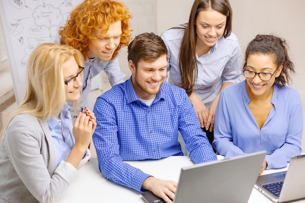 business, office and startup concept - smiling creative team with with laptop computers working in office