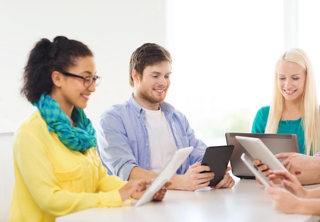 business, office, technology and startup concept - smiling creative team with table pc and laptop computers working in office