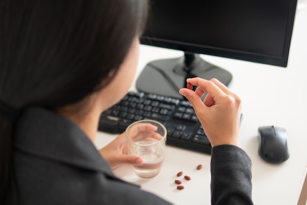 Business office worker employee feels sick from working so taking medicine to relief pain