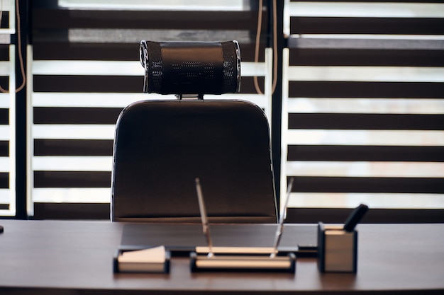 Business office workplace. Work place for chief, boss or other employees. Table and comfortable chair. Light through the half open blinds