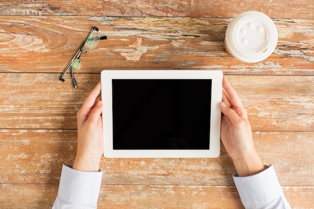 business, onderwijs, mensen en technologie concept - close-up van vrouwelijke handen met tablet pc-computer met koffiekopje en bril