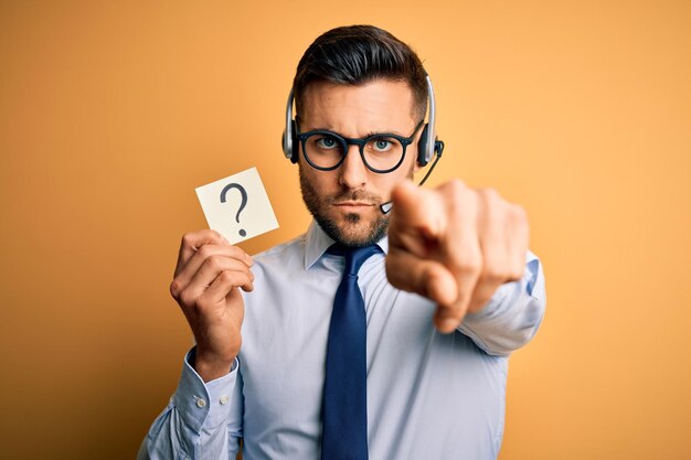 Photo business operator man with customer service headset from call center showing question mark pointing with finger to the camera and to you hand sign positive and confident gesture from the front