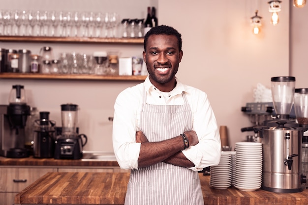 Business owner. Handsome positive man standing in his cafeteria while being ready to work