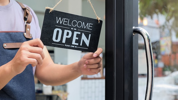 Photo business owner holds an open sign to provide service