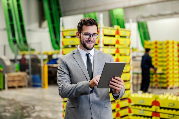 A business owner monitoring works in fruit production factory warehouse over the tablet