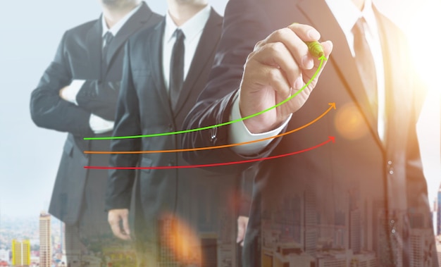 Business partner team standing together with manager\
businessman coach leadership draw graph with three lines double\
exposure effect with cityscape
