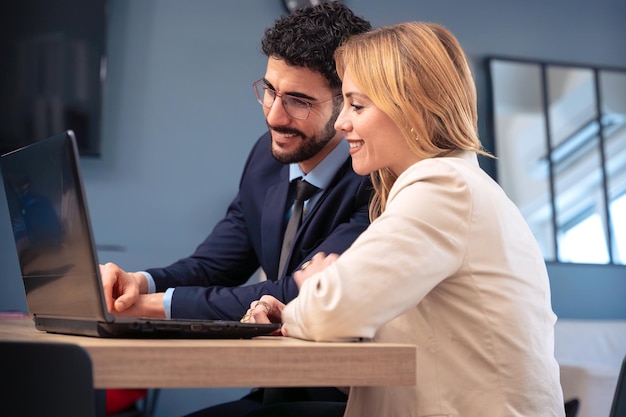 business partners collaborating on laptop in modern office smiling and working