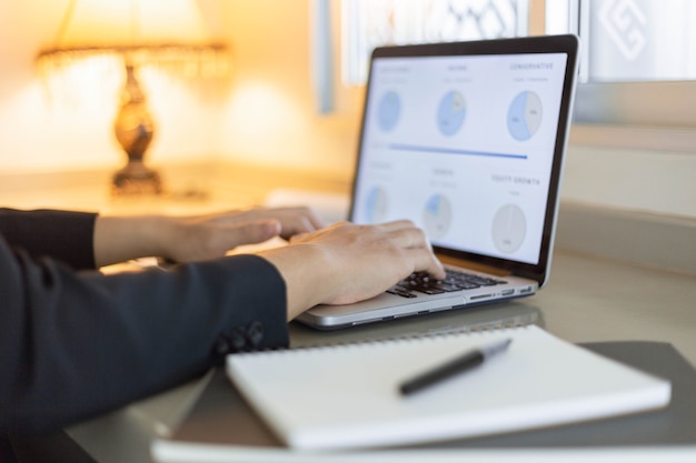 Business partners concept a young businessman using a laptop revising annual sales summary.