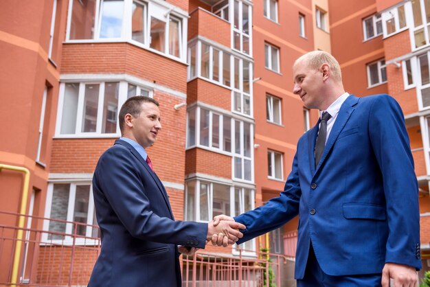 Business partners handshaking before big building outdoors