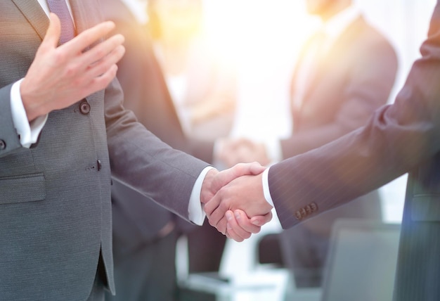 Business partners handshaking over business objects on workplace