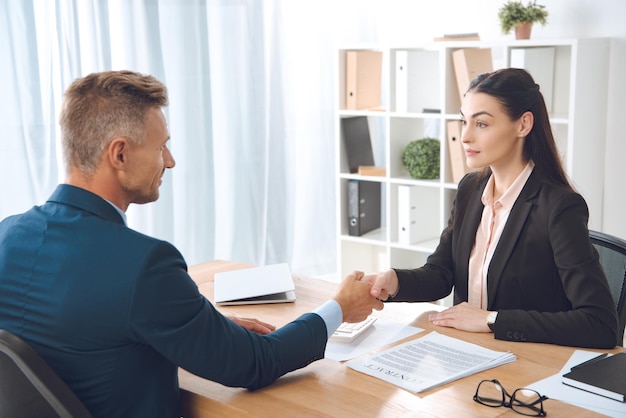 Business partners shaking hands at workplace in office