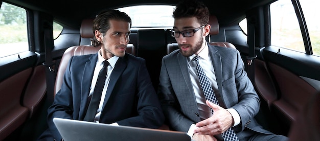 Business partners sitting in a luxury car