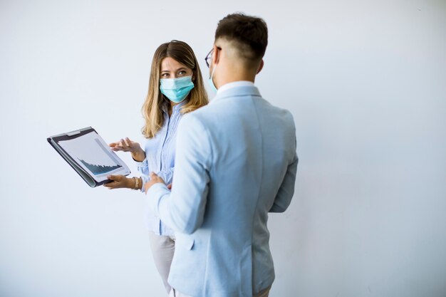 Business partners standing and looking at business results in office  while wearing face masks as an virus protection