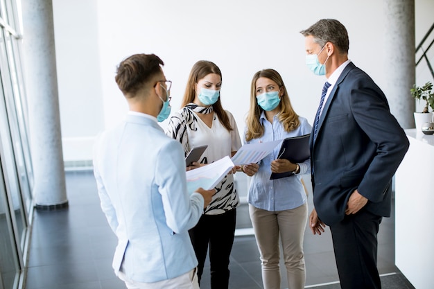 Business partners standing and looking at business results in the office while wearing face masks sa an virus protection