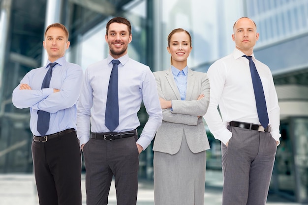 business, partnership and people concept - group of smiling businessmen over business center background