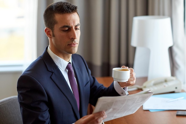写真 ビジネス、人々、マスメディアのコンセプト – ビジネスマンがホテルの部屋で新聞を読み、コーヒーを飲む