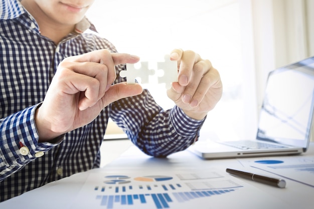 Photo business people assembling holding two blank jigsaw puzzle  pieces in his hands conceptual of solving a problem, growth and development.