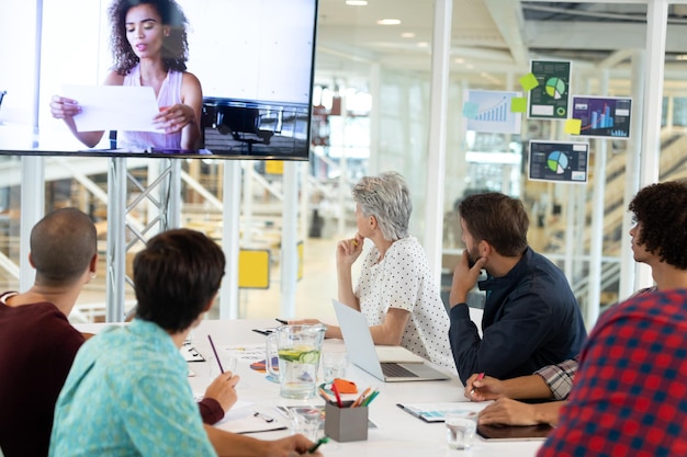 Foto persone d'affari che partecipano a una videoconferenza in una sala conferenze in un ufficio moderno