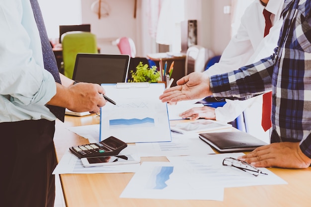 Business people brainstorming at office desk, they are analyzing financial reports and pointing out financial data on a sheet