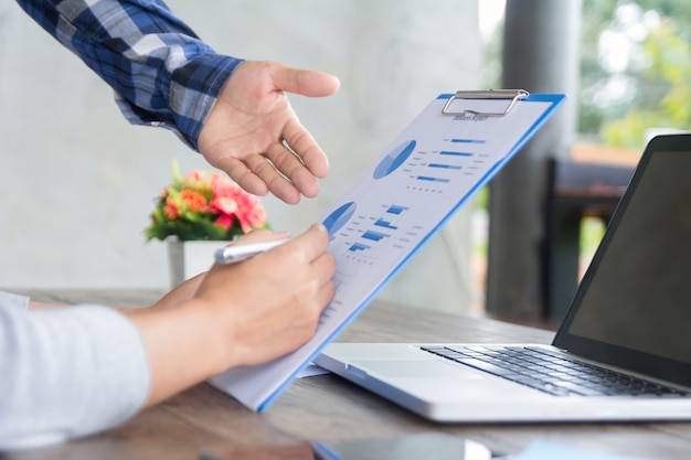 Business people brainstorming at office desk, they are analyzing financial reports and pointing out financial data on a sheet