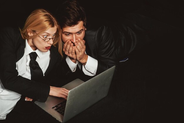 Деловые люди пара коллег по бизнесу, изолированные на черном фоне, с помощью портативного компьютера