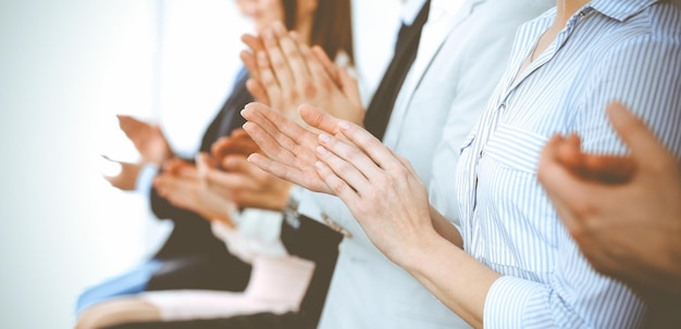 Foto uomini d'affari che applaudono e applaudono a riunioni o conferenze, primo piano delle mani. gruppo di uomini e donne d'affari sconosciuti in un moderno ufficio bianco. successo di lavoro di squadra o concetto di coaching aziendale.