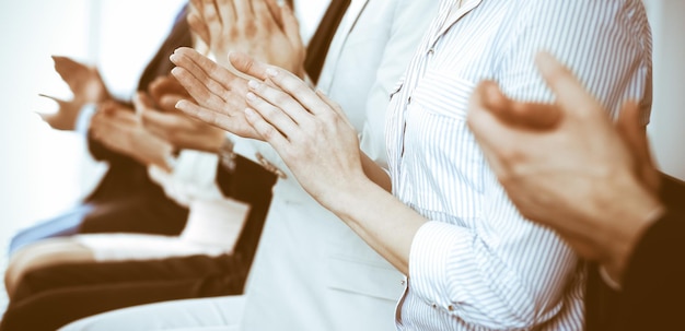 Photo business people clapping and applause at meeting or conference, close-up of hands. group of unknown businessmen and women in modern white office. success teamwork or corporate coaching concept.