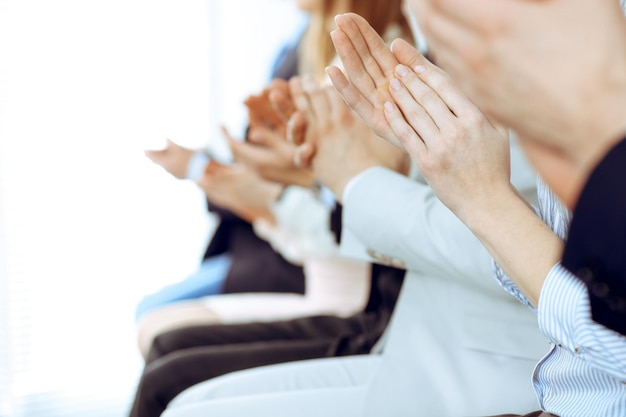 사업가들은 회의나 회의에서 박수를 치고 박수를 치며 손을 클로즈업합니다. 현대 흰색 사무실에서 알 수 없는 기업인과 여성 그룹. 성공 팀워크 또는 기업 코칭 개념.