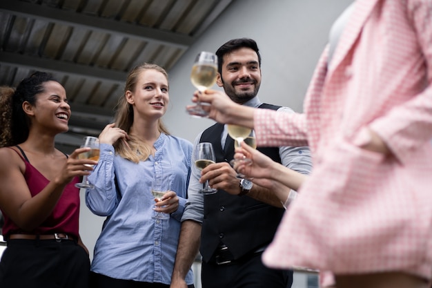 ビジネスマンは成功した仕事を祝うためにグラスをチリンと鳴らし、ワインを飲みます。ビジネスマンのグループは笑顔でワインを飲むことによって祝います。