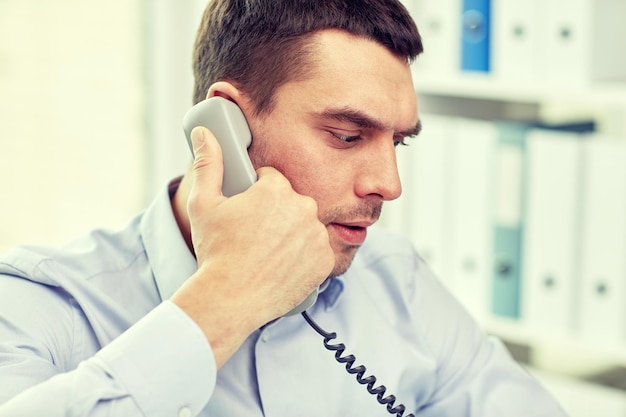 business, people and communication concept - face of angry businessman calling on phone in office