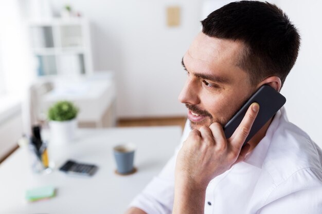 business, people, communication and technology concept - businessman calling on smartphone at office