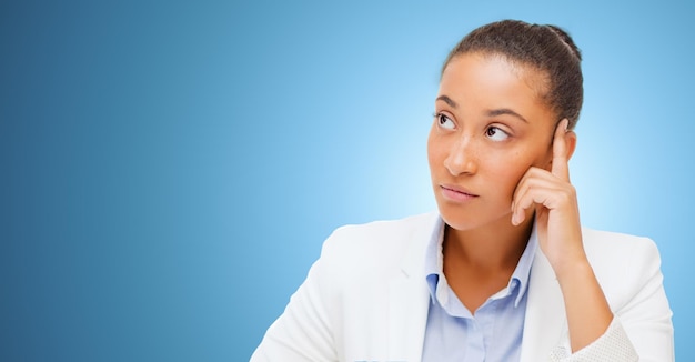 business and people concept - african american businesswoman looking up and thinking over blue background