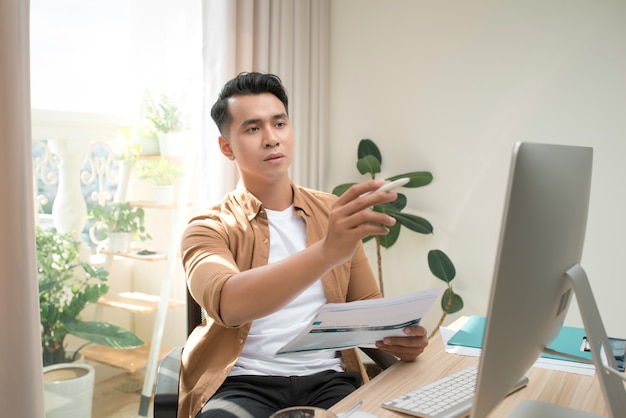 Business and people concept - businessman with papers and laptop computer working at office