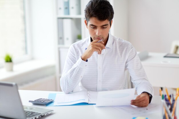 business and people concept businessman with papers and laptop computer working at office