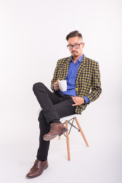 Business and people concept - Handsome man sits in his chair and holding a cup on white background.