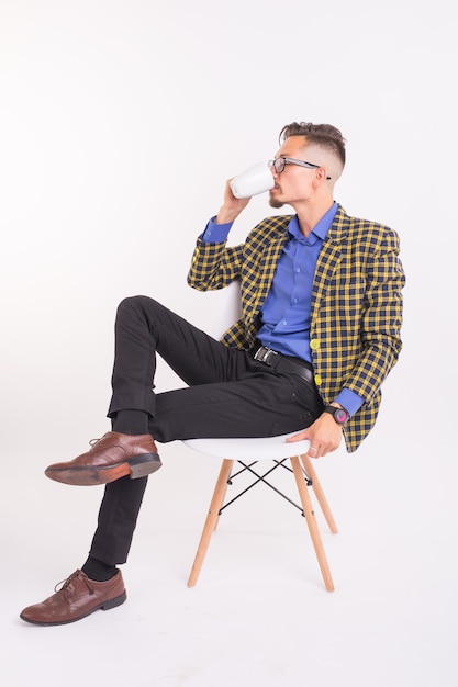 Business and people concept - Handsome man sits in his chair and holding a cup on white background.