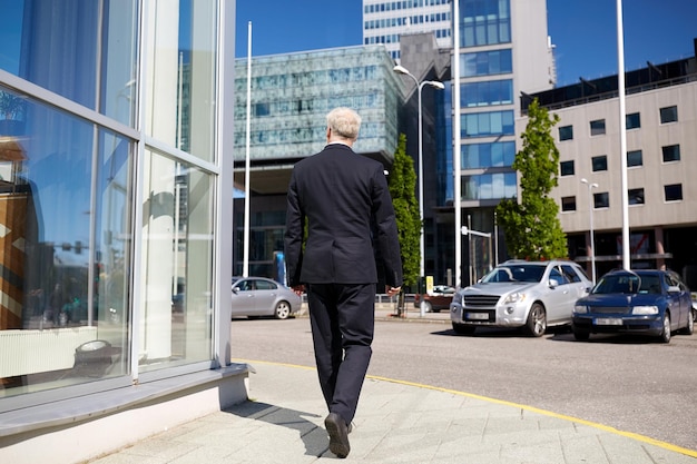 business and people concept - senior businessman walking along city street