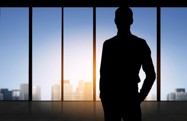 business and people concept - silhouette of business man over office window background