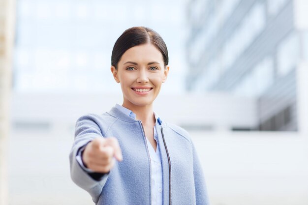 business and people concept - young smiling businesswoman over office building