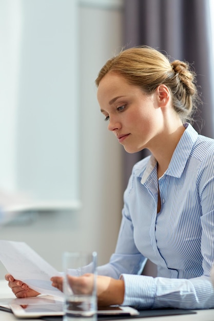 business, people and crisis concept - businesswoman sitting sad and reding document in office